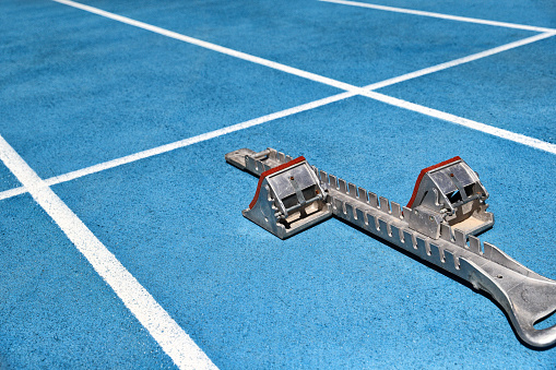 Starting blocks on blue running tracks lanes at track and field stadium. Sport accessory.