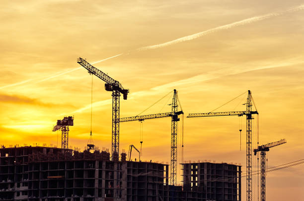 istock Construction site with frames of multistory buildings and cranes at yellow evening sky with sunlight 1371379995