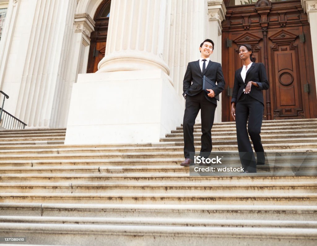 Legal Business People A well dressed man and woman smiling as they as they walk down steps of a courthouse  building. Could be business or legal professionals. Politician Stock Photo