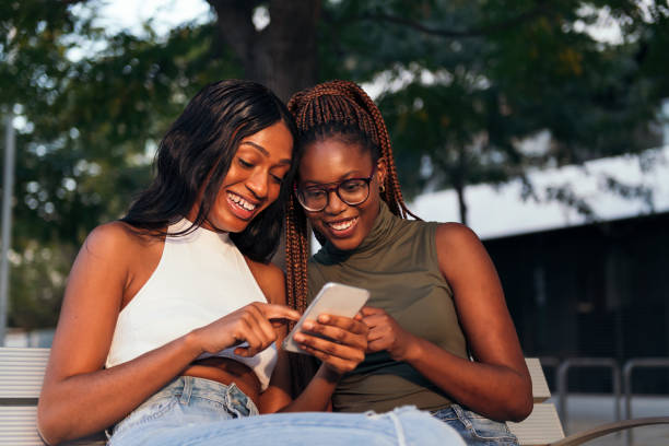 istock friends having fun on a park bench looking phone 1371394558