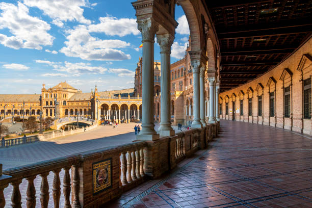 blick vom überdachten portikus der plaza de espana oder des spanischen platzes in sevilla, spanien, mit blauem himmel und wolken. - plaza de espana seville spain parque maria luisa stock-fotos und bilder