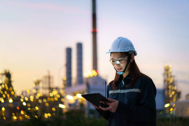 ingegnere petrolchimico donna asiatica che lavora di notte con tablet digitale all'interno della fabbrica dell'industria dell'impianto di raffineria di petrolio e gas di notte per il controllo di qualità della sicurezza dell'ispettore. - petrochemical plant oil refinery factory outdoors foto e immagini stock