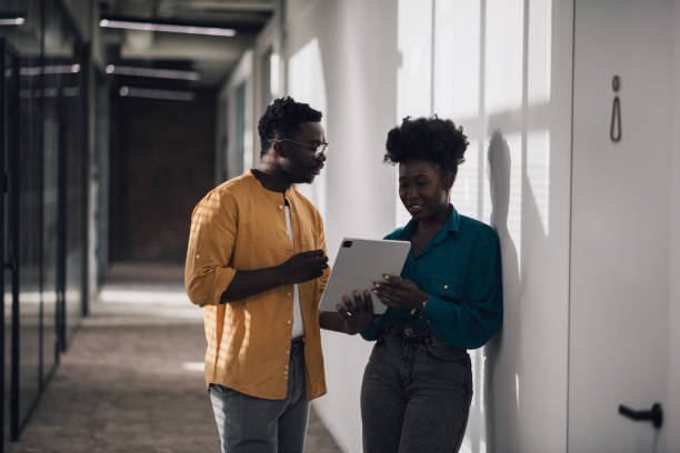 istock Two black millennial businesspersons talking in shared office space hallway 1371405335