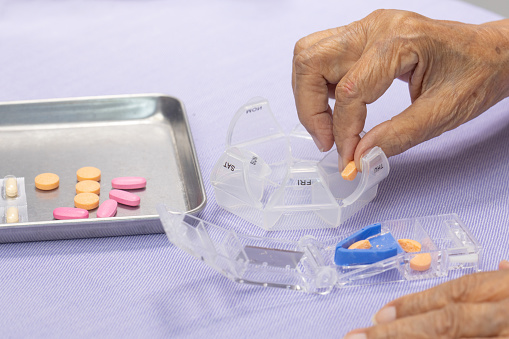 Elderly woman using pill splitter or pill cutter .