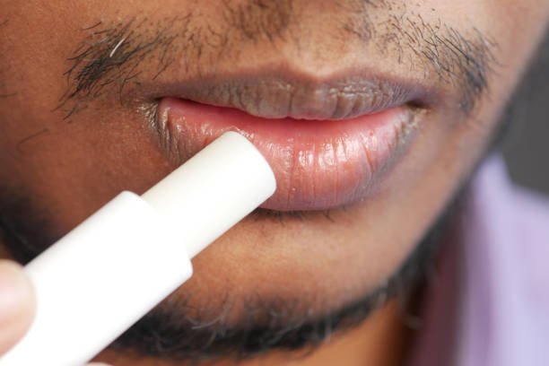 istock young man applying moisturising lip balm on lips 1371410494
