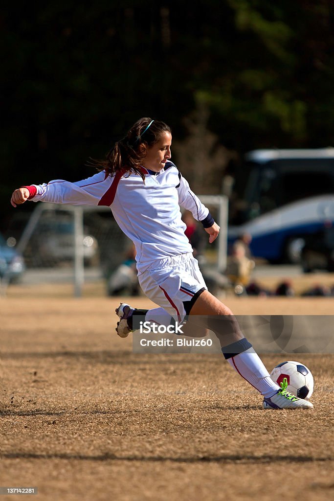 Mujer jugador de fútbol s'extiende hasta patear pelota - Foto de stock de Fútbol femenino libre de derechos