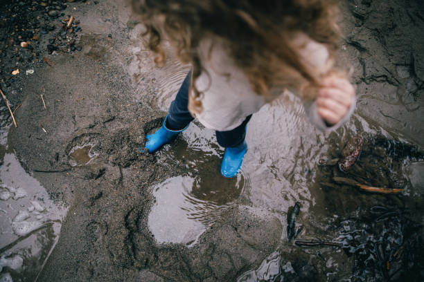 istock Little Girl Splashing Mud Puddles 1371423260