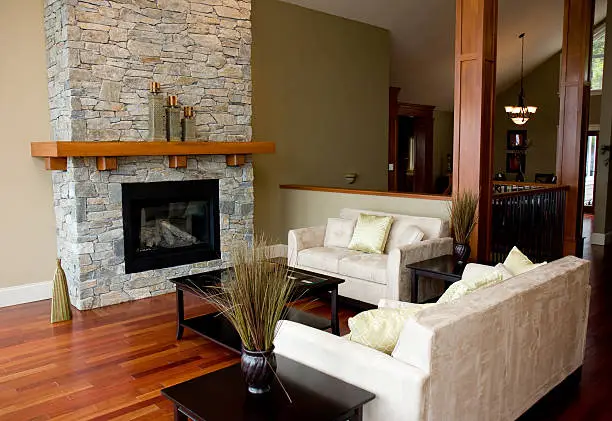 A stone fireplace and beautiful hardwood floors highlight the living room of a new luxury home.