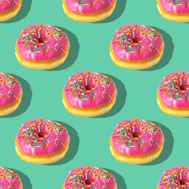 istock Repeating pattern of pink donuts on a green background. Flat lay 1371428158
