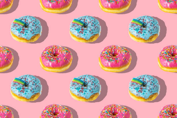 istock A repeating pattern of pink and blue rainbow donuts on a pink background 1371428169