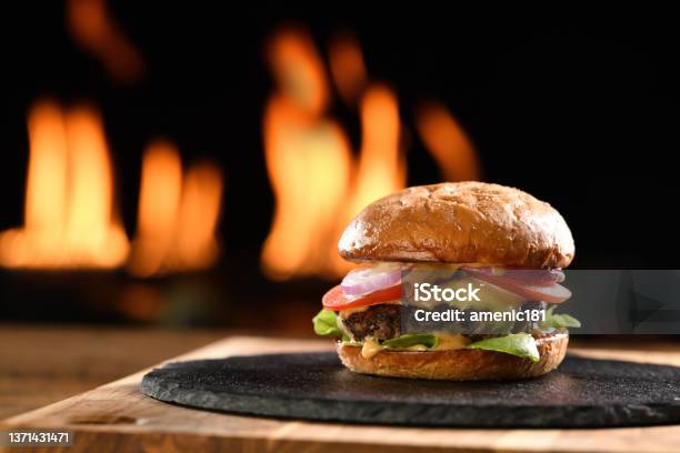 Beef Cheeseburger On Black Plate With Flames In Background Stock Photo - Download Image Now