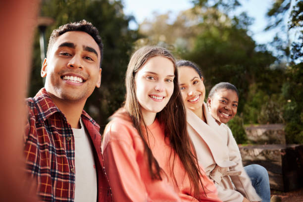 istock Portrait of four young university students taking selfies while sitting outside on campus during their break 1371432106