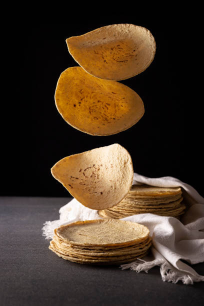 Tortillas Falling Corn Tortillas. Food made with nixtamalized corn, a staple food in several American countries, an essential element in many Latin American dishes. tortilla flatbread stock pictures, royalty-free photos & images