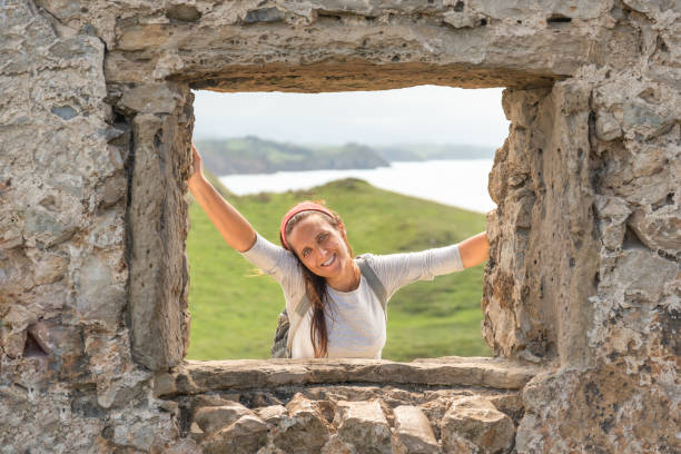happy female traveler near ancient ruin and sea - beach stone wall one person imagens e fotografias de stock