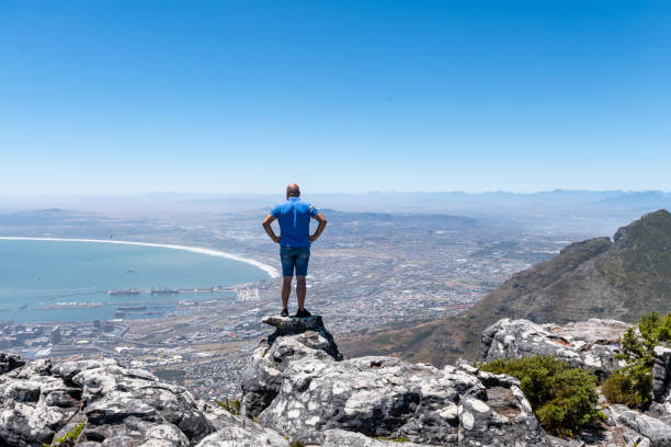 man standing on top of table view mountain in cape town - sky sea town looking at view imagens e fotografias de stock