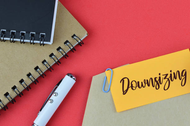istock Top view of notebook, pen and memo note written with text DOWNSIZING. 1371460542