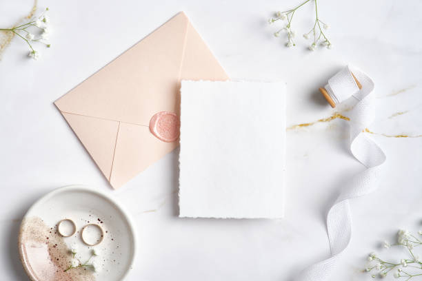 istock Elegant wedding stationery set. Flat lay wedding invitation card template, pastel pink envelope, silk ribbon, golden rings, flowers on marble desk. 1371464362