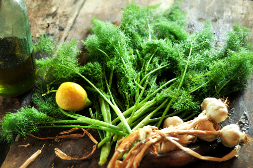 A bunch of fresh organic fennel on a wooden vintage rustic table with lemon and garlic