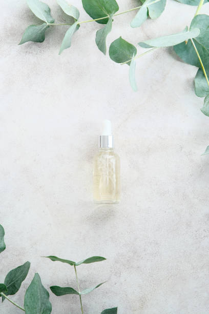 istock Transparent dropper bottle with serum lotion or essential oil on stone table with eucalyptus leaves. Skin care cosmetics concept. 1371470592
