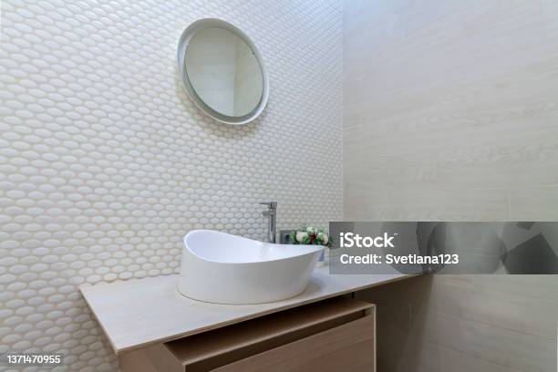 White Washbasin With Faucet On Wooden Countertop In Minimalist Modern Bathroom Scandinavian Interior With Tiled Mosaic Wall Wall And Round Mirror Copy Space And Nobody Stock Photo - Download Image Now