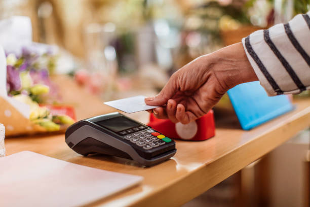 This has become the standard way of paying Unrecognizable person making a contactless credit card payment at the flower shop paid stock pictures, royalty-free photos & images