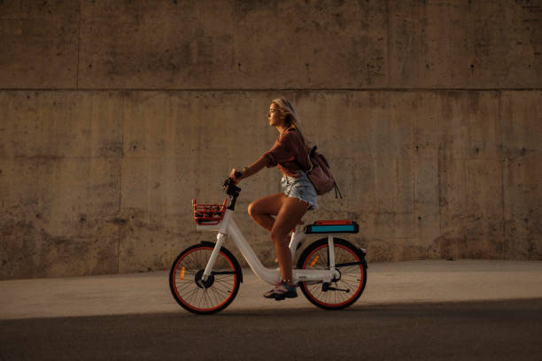 Having the time of her life Side shot of a young pretty blond woman riding a city bicycle during sunset electric bicycle stock pictures, royalty-free photos & images
