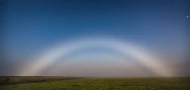 Moonbow or nocturnal rainbow at night, mystic night landscape