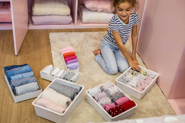 Happy girl neatly roll folded underwear and socks in plastic container box Marie Kondo method stock photo