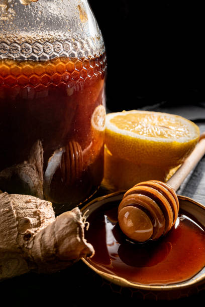 istock Honey in jar with honey dipper, ginger and lemon on black background. 1371484317