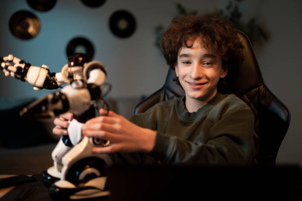 istock Cheerful, intelligent student sitting at desk at home constructing robotic device in spare time, child smiles develops hobby 1371486764
