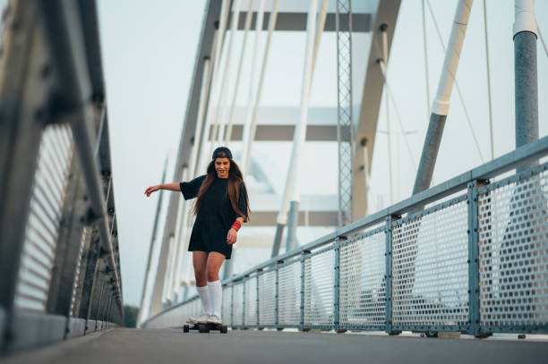 istock Young woman riding her longboard on the bridge 1371487035
