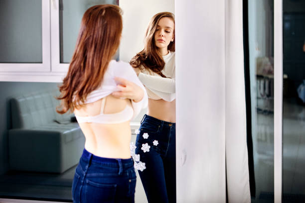 istock Woman undresses in front of mirror inside. 1371488953