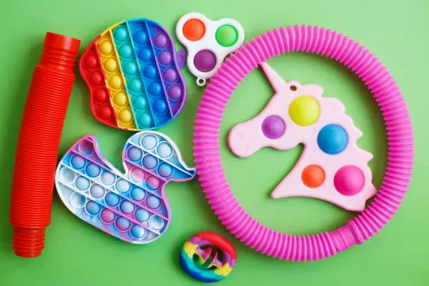 Photo of colorful antistress sensory fidget toys on a green background.