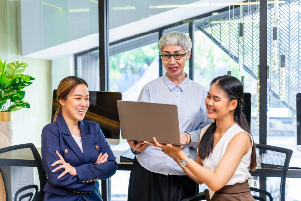 Senior businesswoman team leader is guiding young member to business success by showing information in laptop computer for goal achievement for startup and creativity project concept Senior businesswoman team leader is guiding young member to business success by showing information in laptop computer for goal achievement for startup and creativity project teacher retirement party stock pictures, royalty-free photos & images