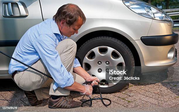 Foto de Inflating Pneus e mais fotos de stock de Adulto - Adulto, Ajoelhar, Calota