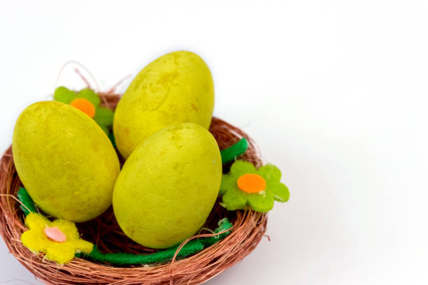 Green eggs surrounding a yellow one on white square plate isolated on white background.