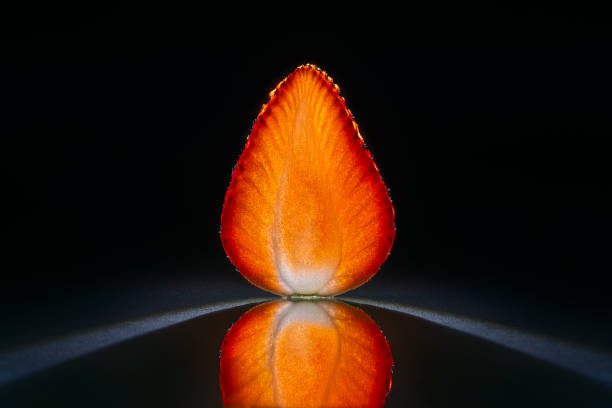 Slice of a strawberry isolated in dark black background with reflection