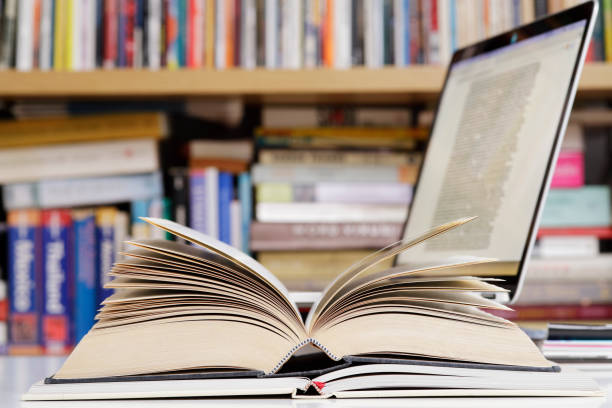 istock Close up of open books and  laptop computer at the library 1371497301