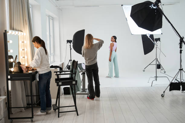 istock Photographer standing and shooting model while make up artist standing at her workplace 1371501017