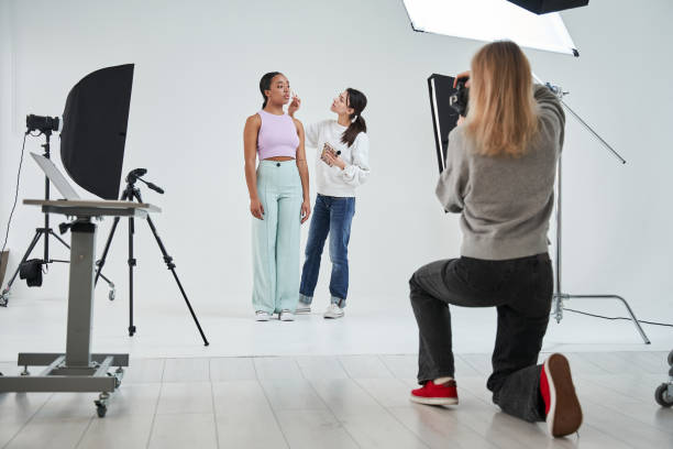 istock Make-up artist standing near the multiracial model and applying cosmetics 1371501021