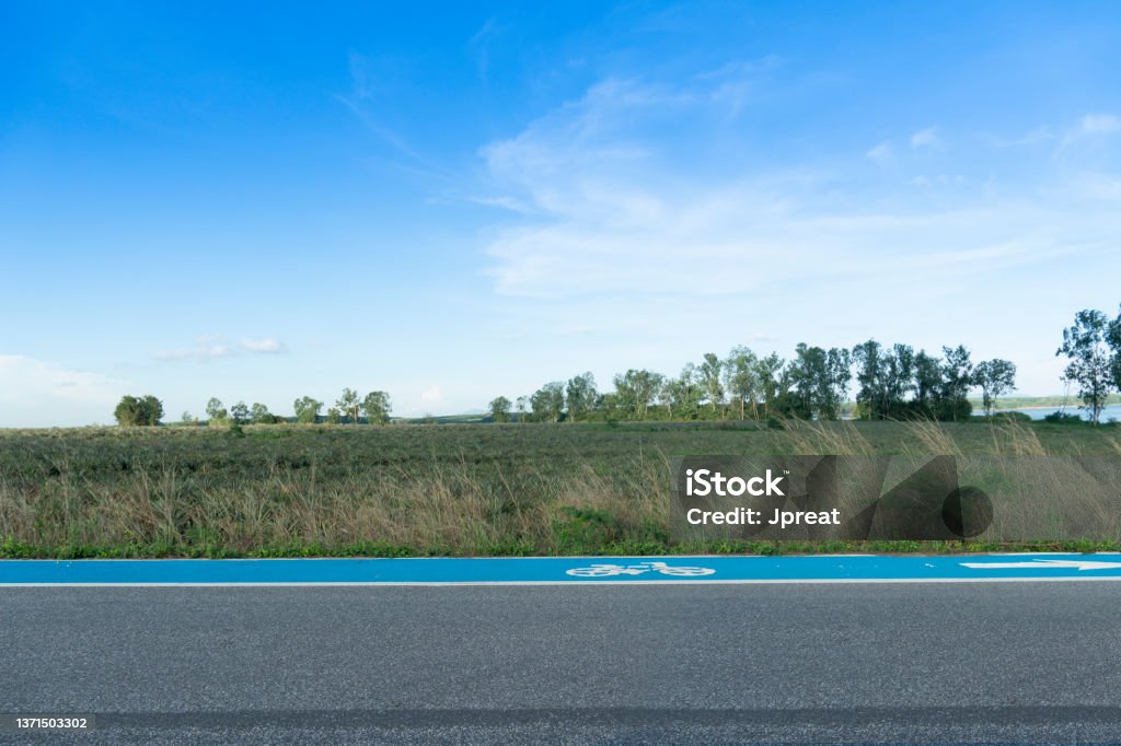 Horizontal and Landscape view of beside asphalt road with bike lens blue color. Horizontal and Landscape view of beside asphalt road with bike lens blue color. with nature of green grass and pineapple plantation under blue sky. Next To Stock Photo