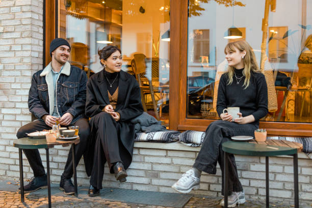 freunde sitzen im straßencafé, trinken kaffee und reden - 20s berlin germany heterosexual couple boyfriend stock-fotos und bilder