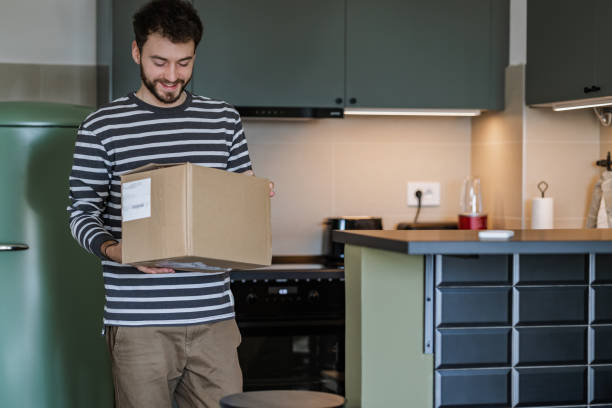 istock Young man holding cardboard box and preparing to open it 1371507125