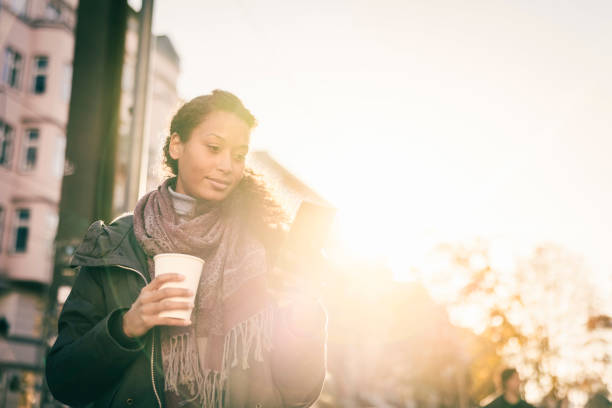 istock Woman with coffee cup texting on smartphone while commuting in the city 1371510137