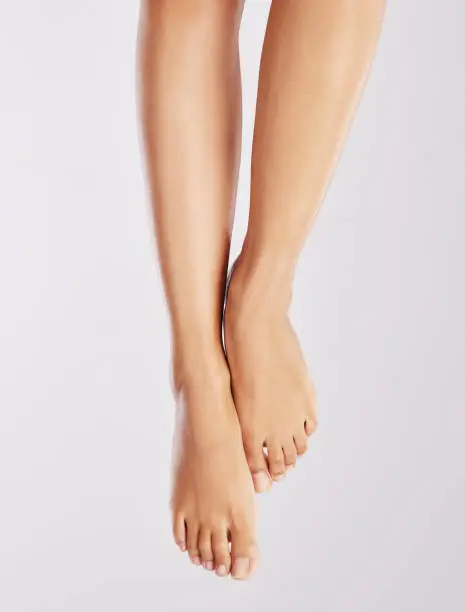 Photo of Cropped shot of a young woman showing off her feet  against a white background