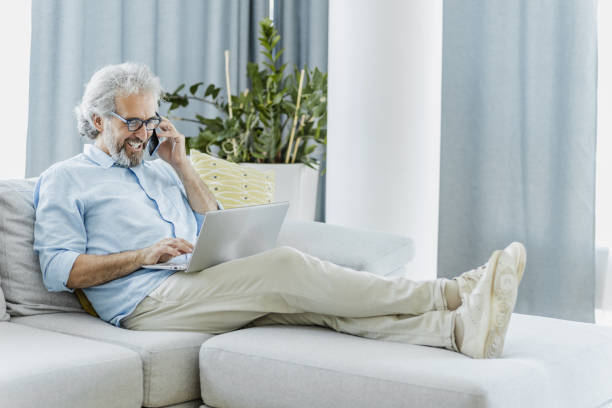 istock Mature handsome man is talking on the phone at home 1371512880