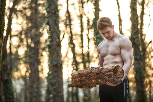 Strong Young Man Doing Sports By Lifting Weights In Nature