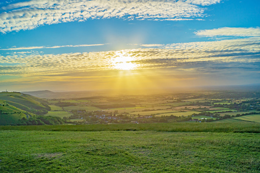 A beautiful sunset throws sunbeams through the clouds at Devil's Dyke