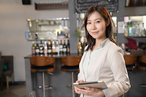 A woman who runs a restaurant with a tablet