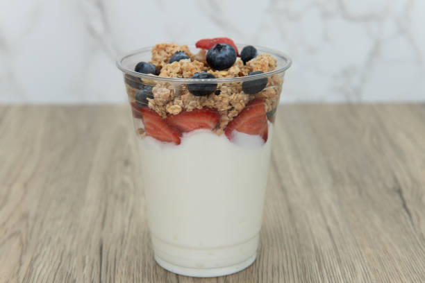 Quick snack to eat after a workout. Complete meal contained in this cup of yogurt, blueberries, strawberries, and granola for plenty of protein and carbohydrates to eat. parfait stock pictures, royalty-free photos & images